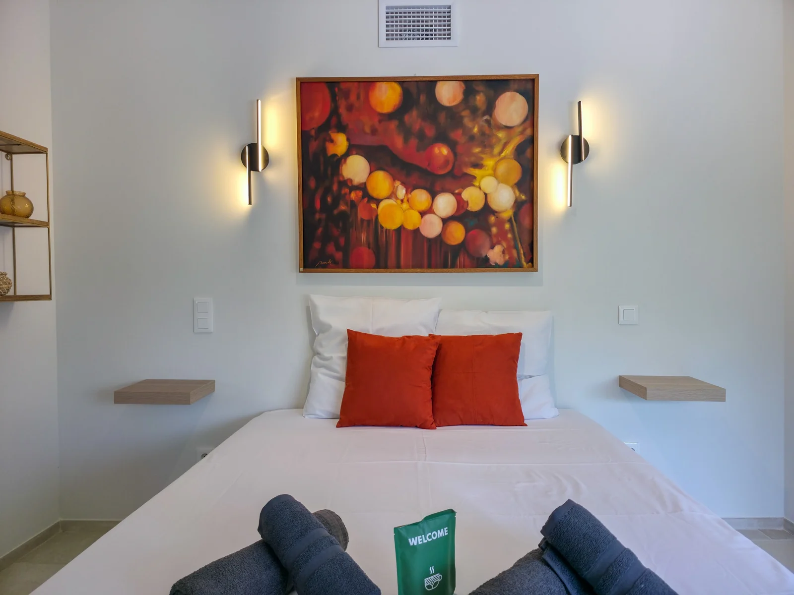 Lit préparé avec linge blanc, serviettes pliées et coussins terracotta